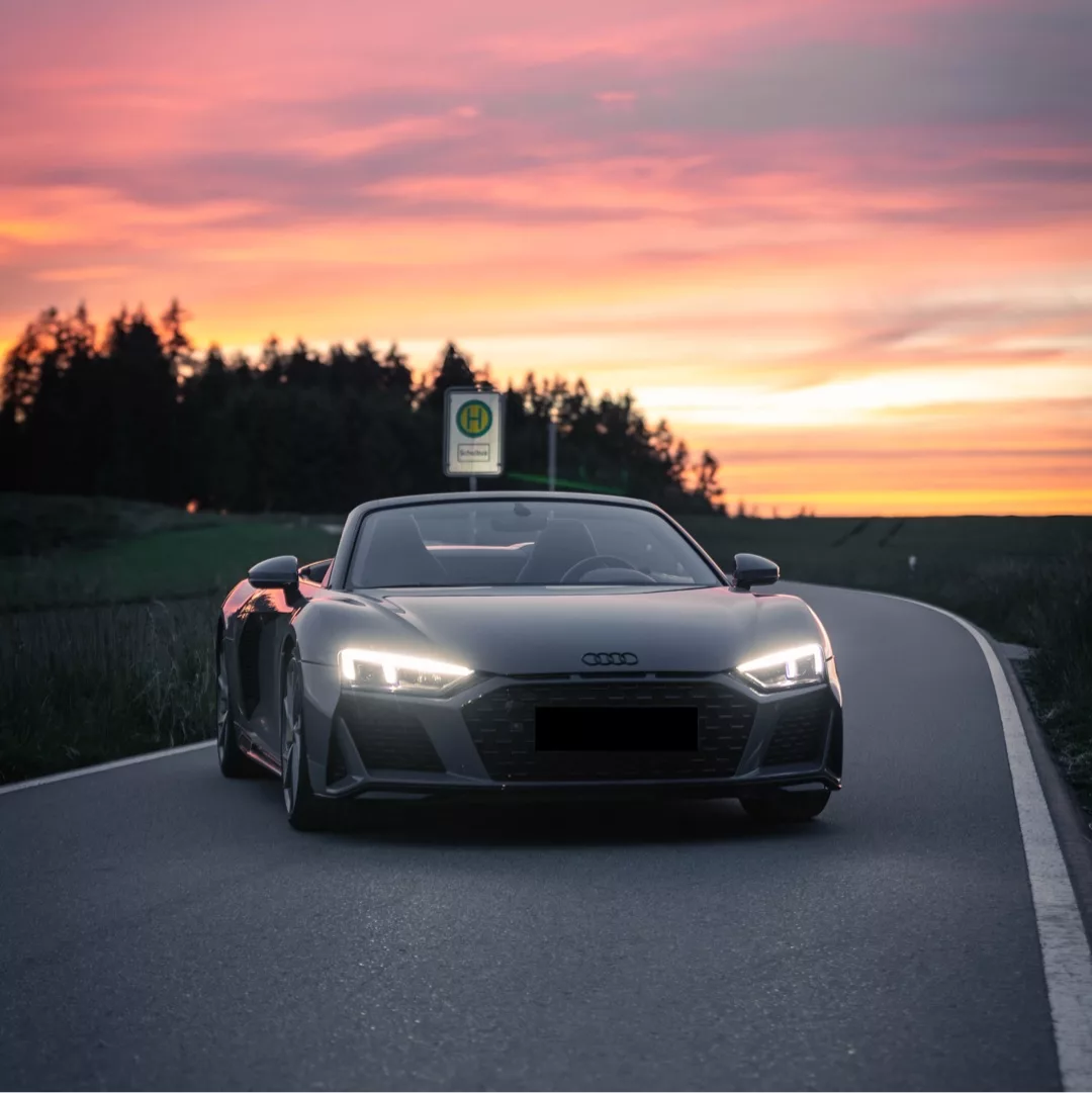Audi R8 V10 Spyder Performance in Schwarz, Frontansicht bei Sonnenuntergang mieten.