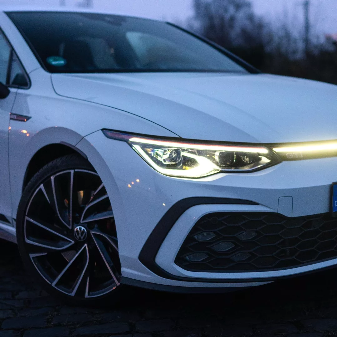 VW Golf 8 GTI in Weiß frontal bei Dämmerung mieten