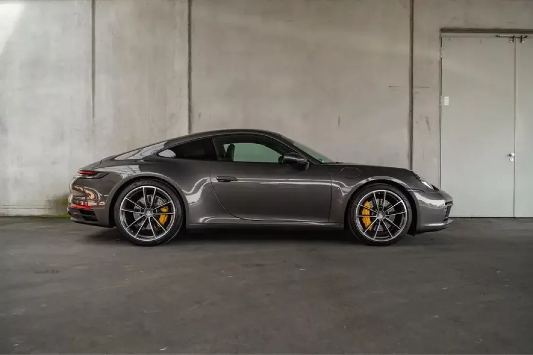 Porsche 911 Carrera S (992) in seitlicher Ansicht vor grauem Hintergrund.