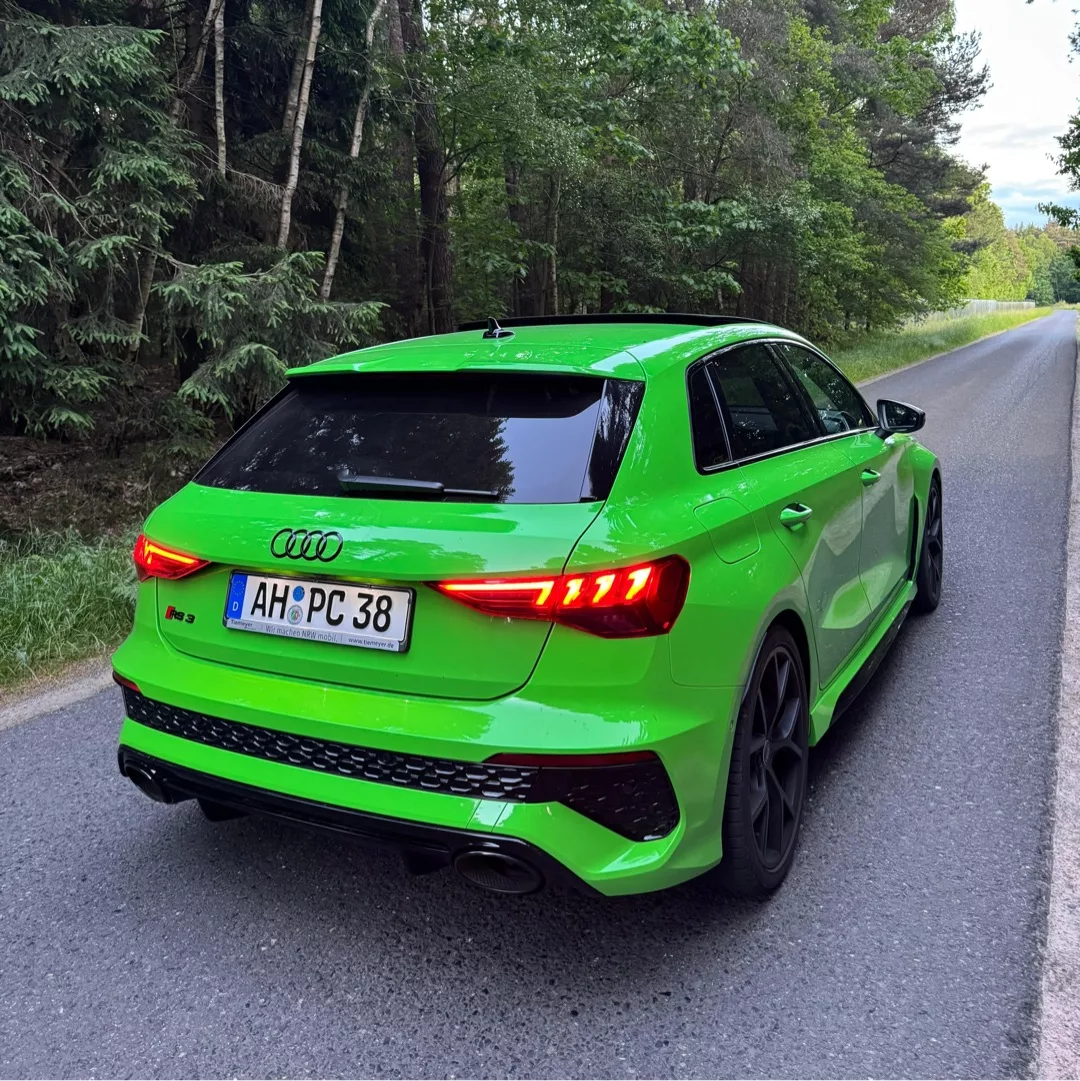 Audi RS3 in Grün auf Landstraße von hinten mieten.
