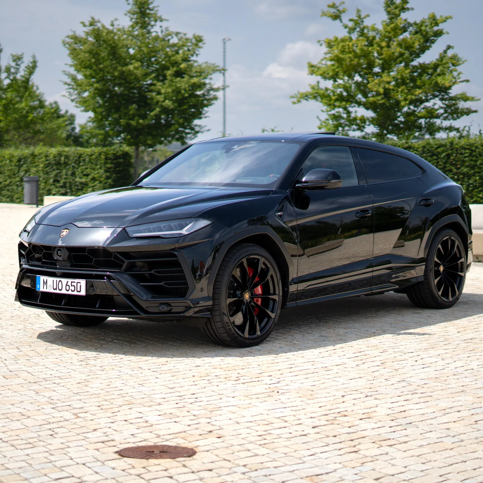 Lamborghini Urus in Schwarz auf Pflasterstein mieten.