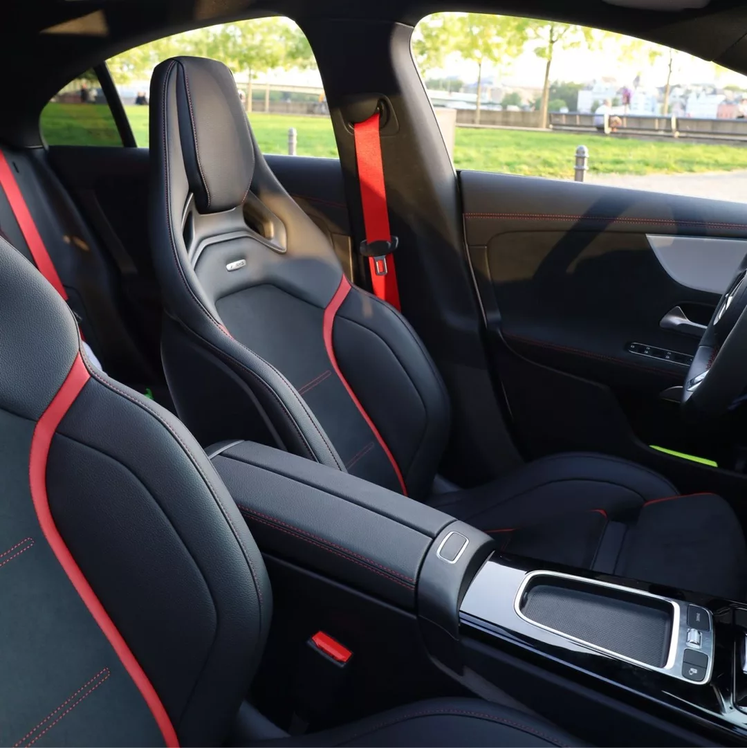Innenraum eines Mercedes AMG CLA45s 4M+ mit stilvollen schwarzen Sitzen und roten Akzenten.