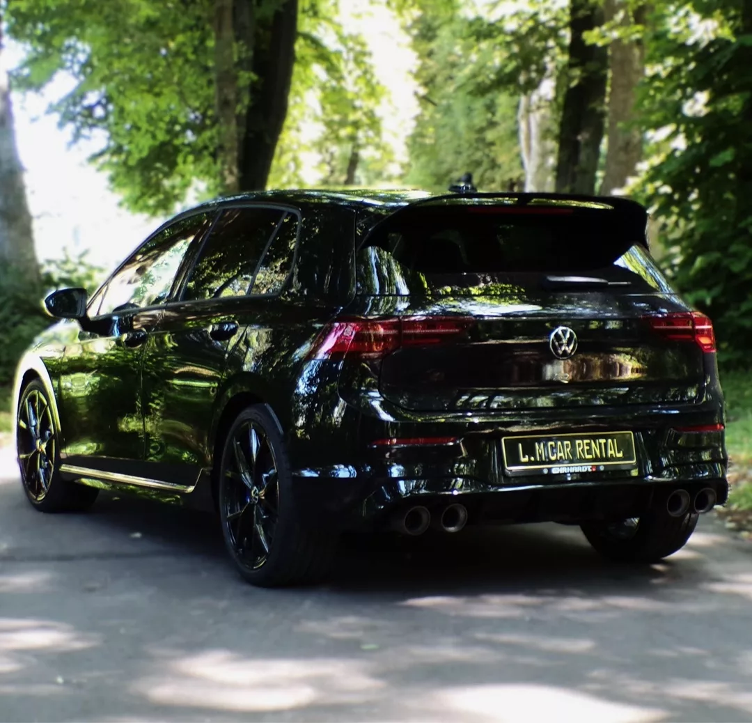 VW Golf 8 R in Schwarz mieten - Rückansicht im Grünen.