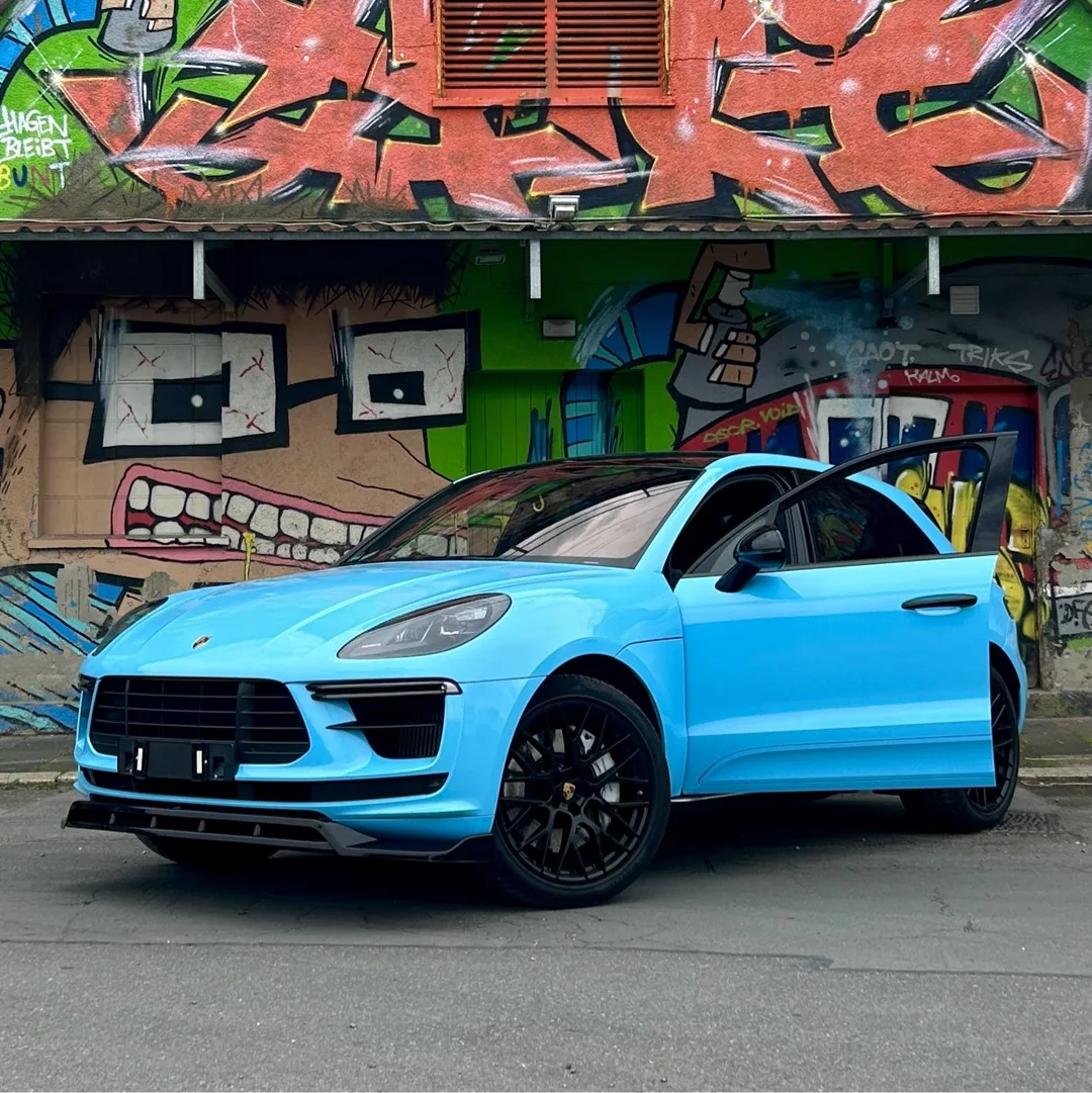 Porsche Macan Turbo in Blau vor Graffiti-Wand mieten.