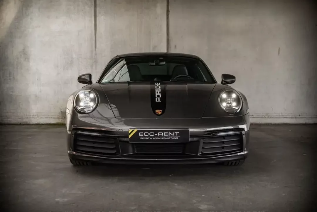 Grauer Porsche 911 Carrera S (992) von vorne in einem urbanen Umfeld.
