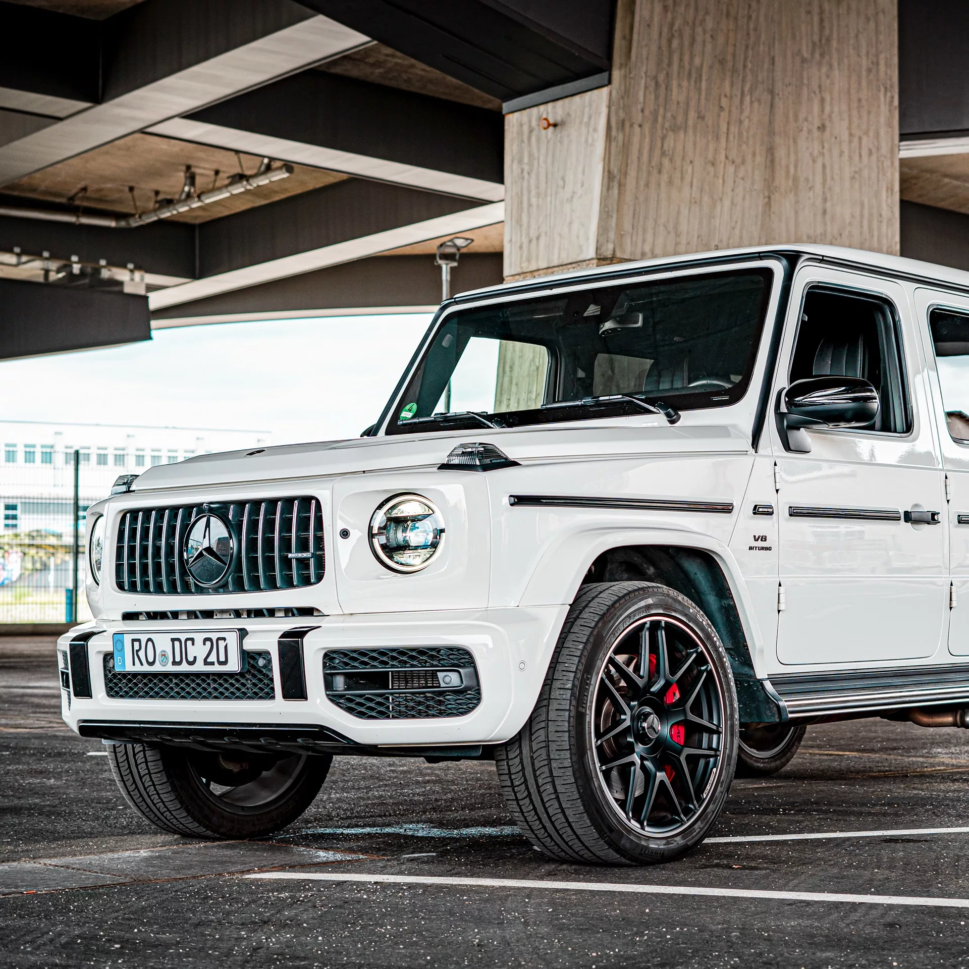 Mercedes G63 AMG in Weiß vor Brückenpfeiler mieten.