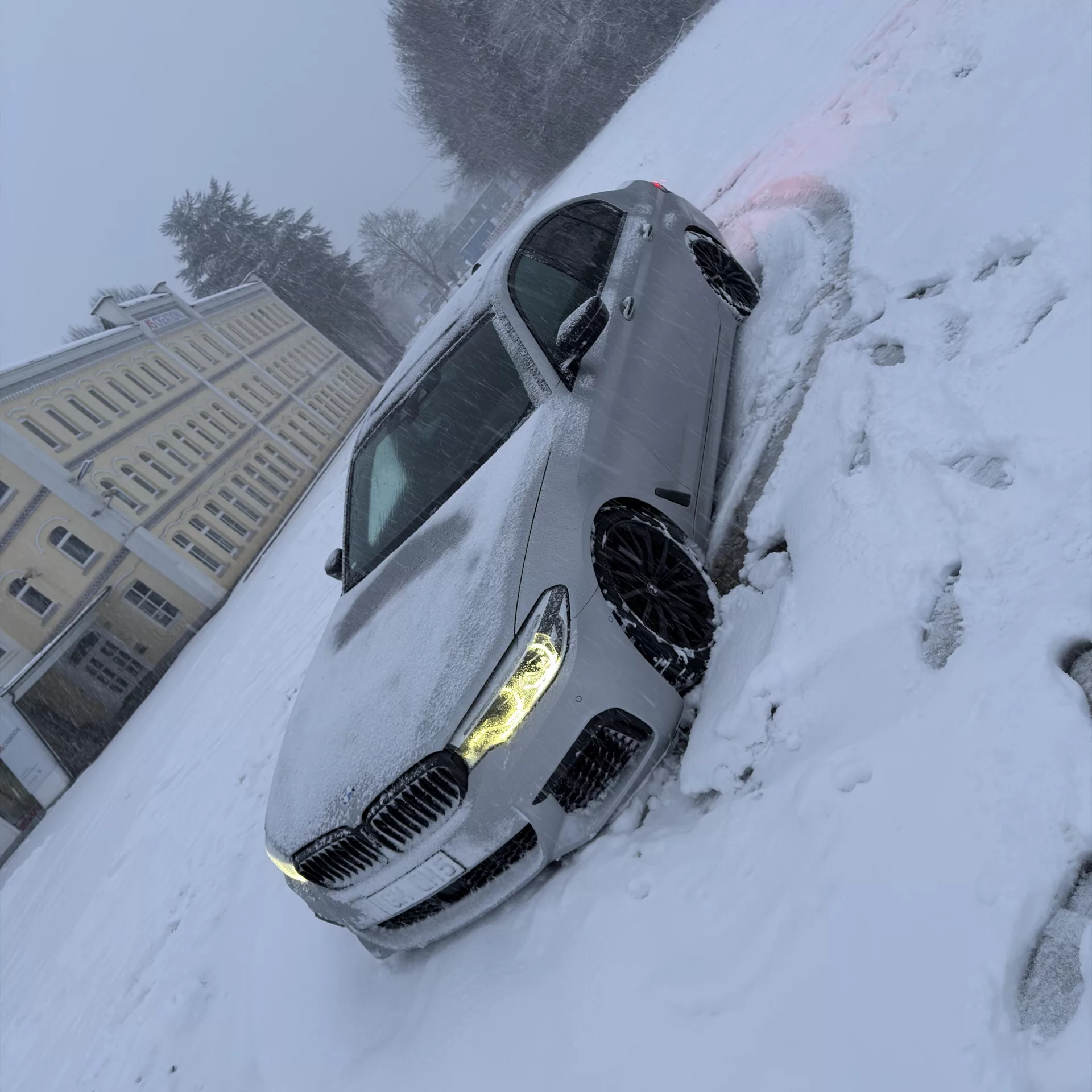BMW m550i in Silber im Schnee von vorne mieten.