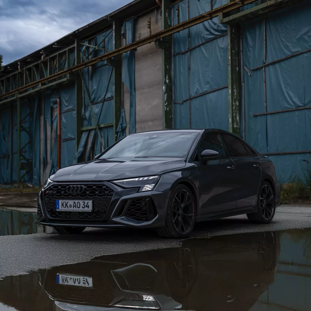 Audi RS3 Limousine in Grau vor Lagerhalle mieten.