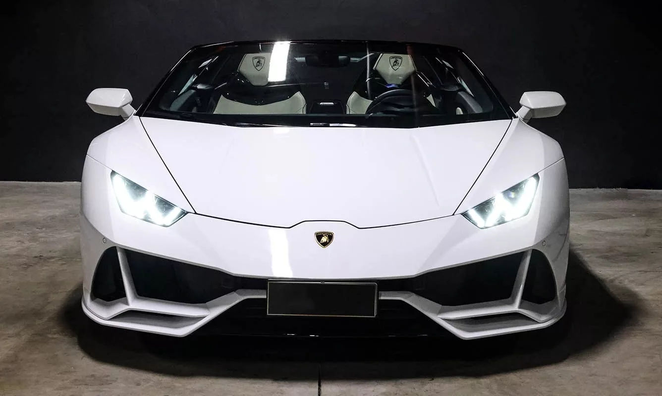 Weißer Lamborghini Huracan EVO Spider vor dunklem Hintergrund.