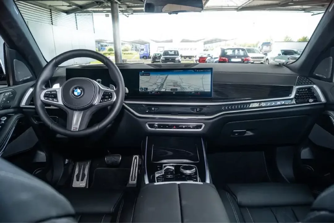 Innenraum eines BMW X7 mit modernem Display und Lenkrad.