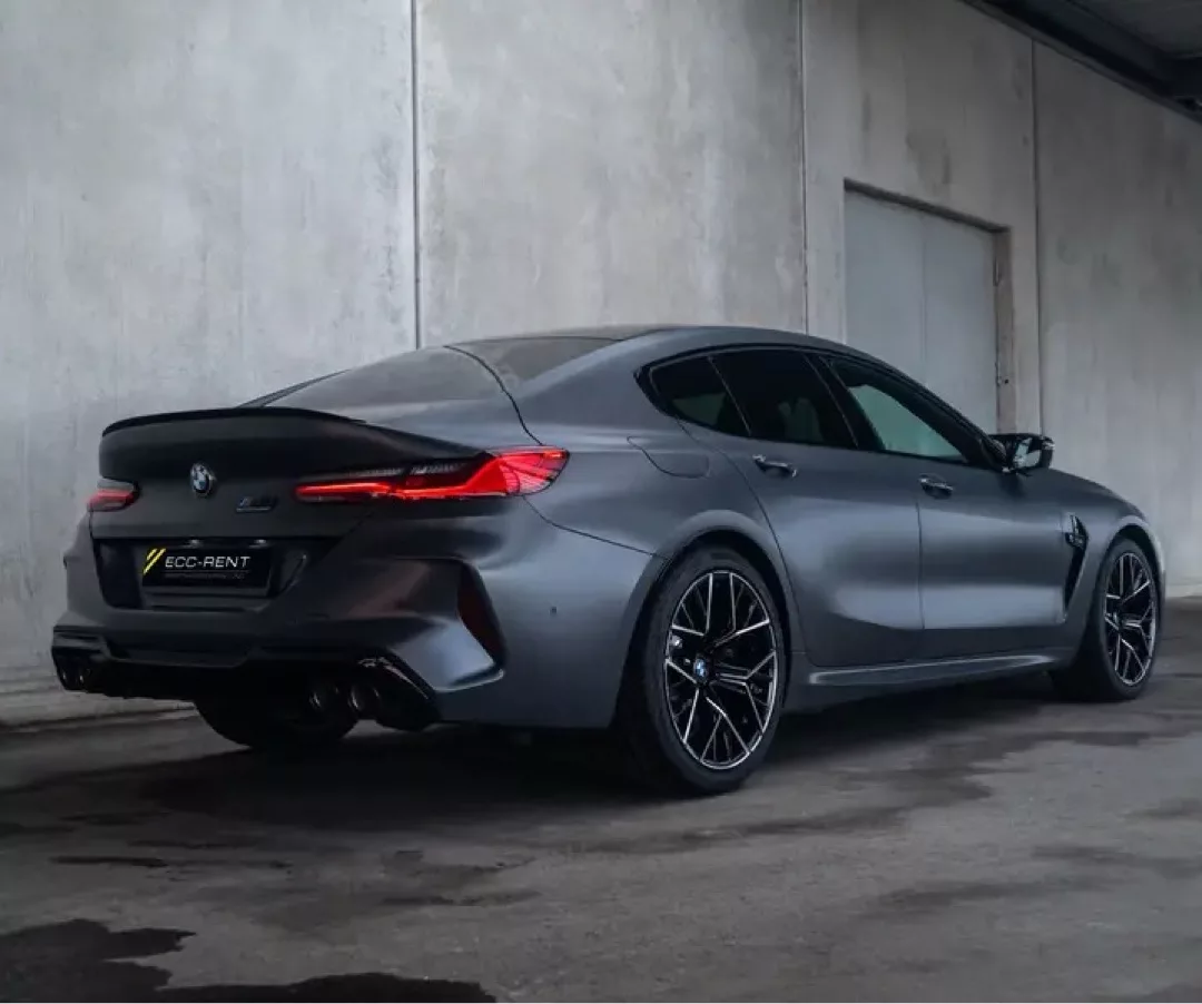 BMW M8 Gran Coupé in modernem Design vor einer grauen Gebäudeoberfläche.