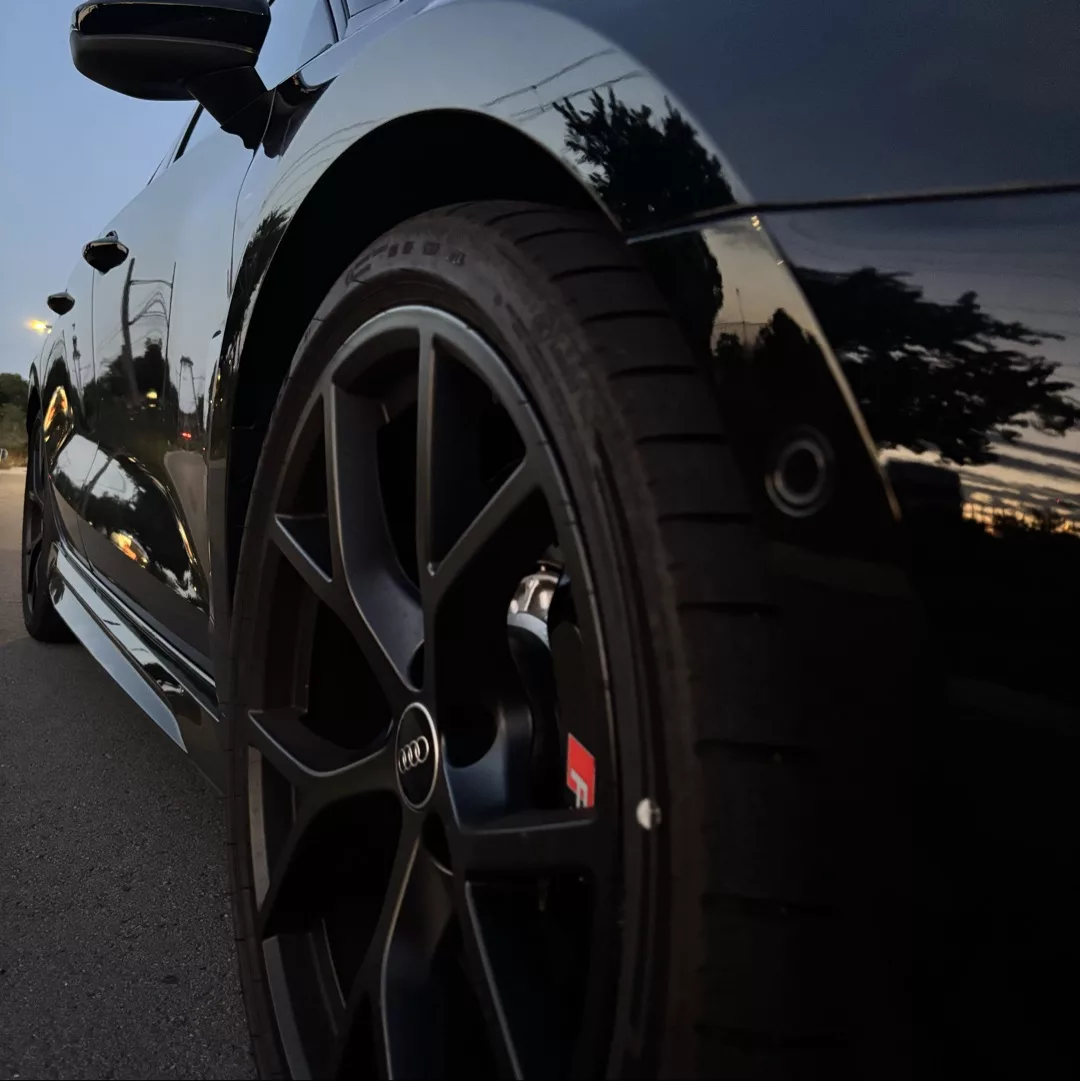 Audi RS3 in Nahaufnahme bei Dämmerung, fokussiert auf die Vorderreifen.