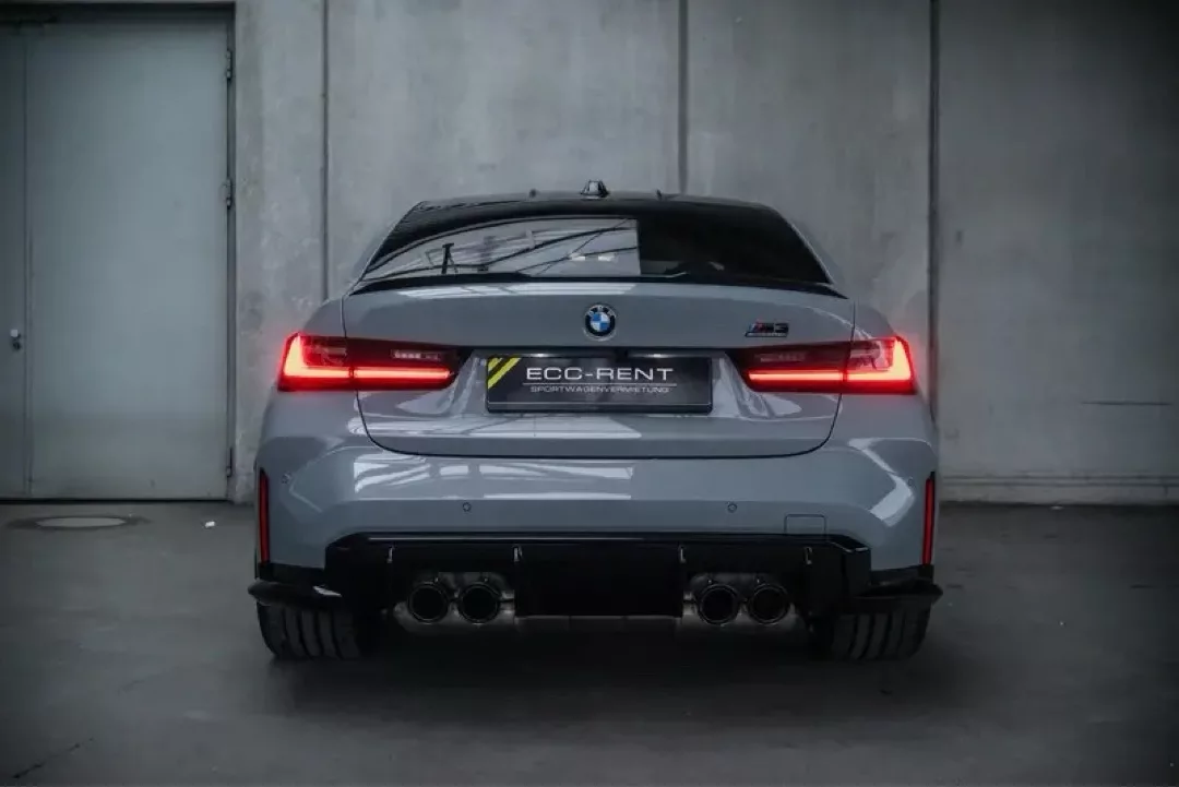 BMW M3 Competition von hinten mit eingeschalteten Rücklichtern.