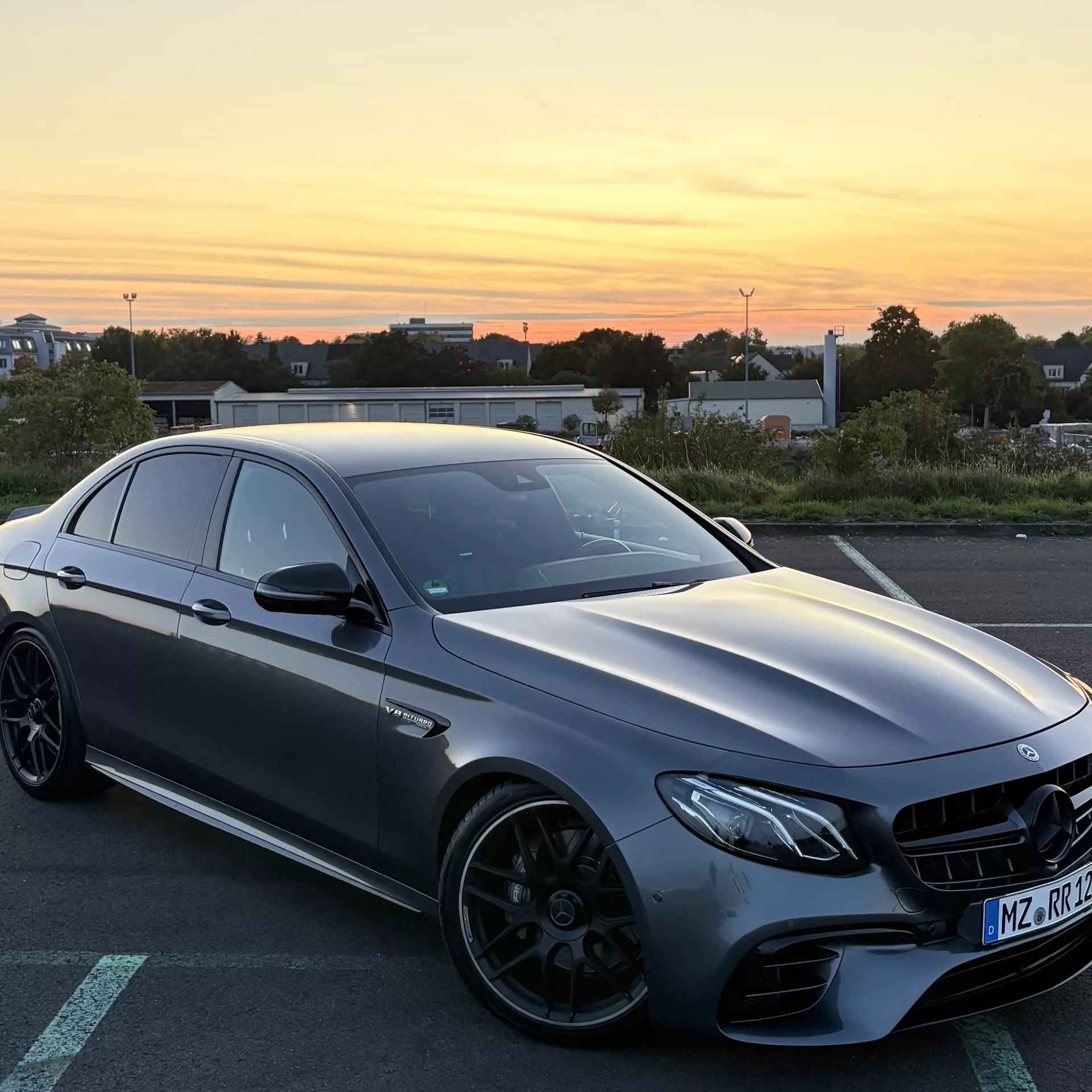 Mercedes AMG E63s Sportwagen in Grau bei Sonnenuntergang mieten