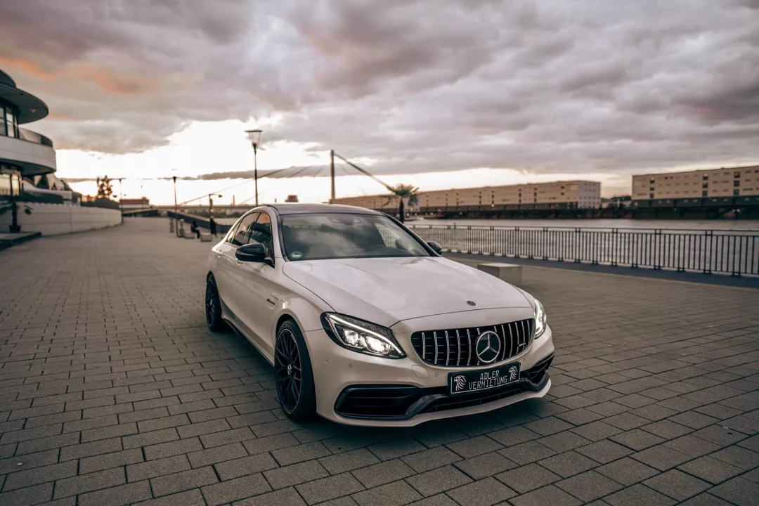 Mercedes C63 AMG in Weiß mieten - Frontansicht bei Sonnenuntergang