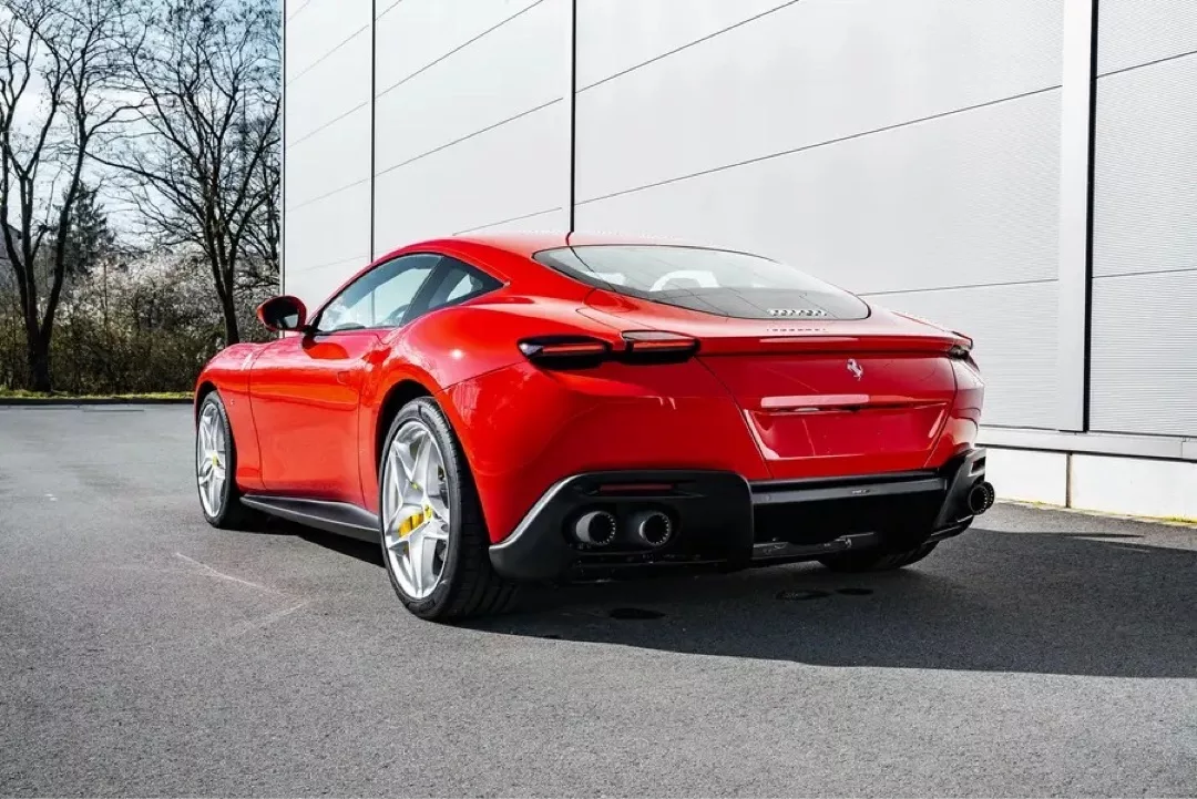 Roter Ferrari Roma vor moderner Gebäudefassade.