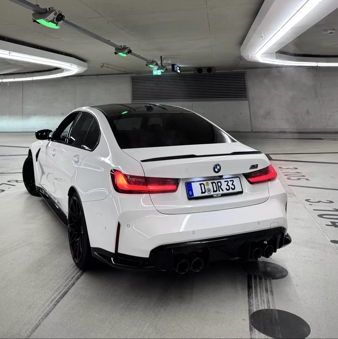 BMW M3 Competition in Weiß von hinten im Parkplatz mieten.