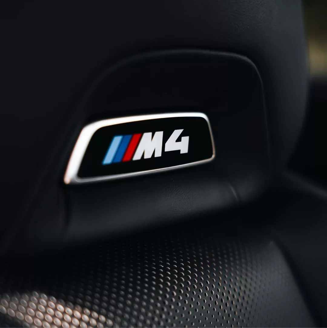 Nahaufnahme des M4-Logos im Innenraum eines BMW M4 Competition xDrive.
