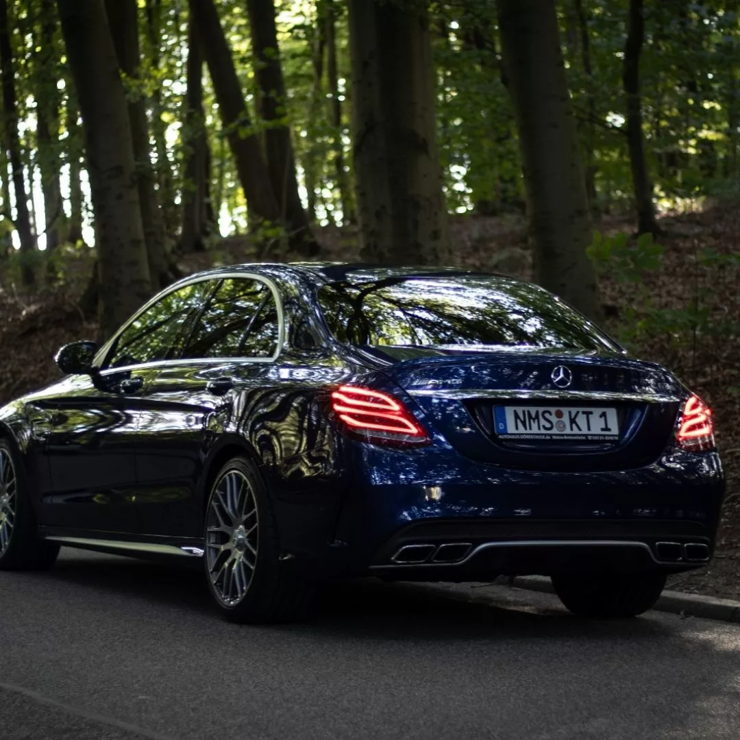 Mercedes Benz c63s AMG in Blau von hinten im Wald mieten.