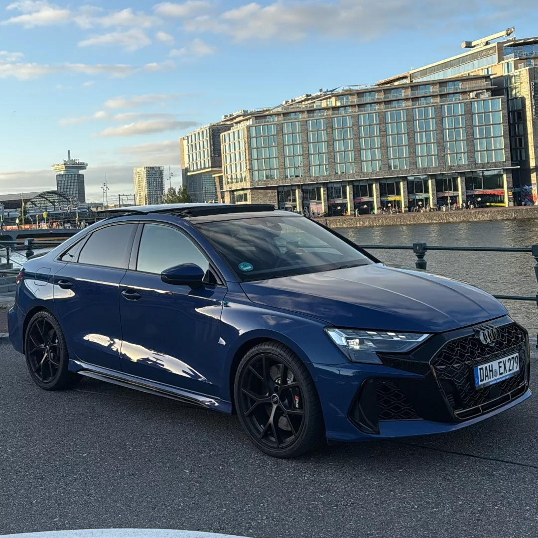 Audi RS3 Facelift 2025 in Blau, Seitenansicht, urbanes Umfeld, mieten.