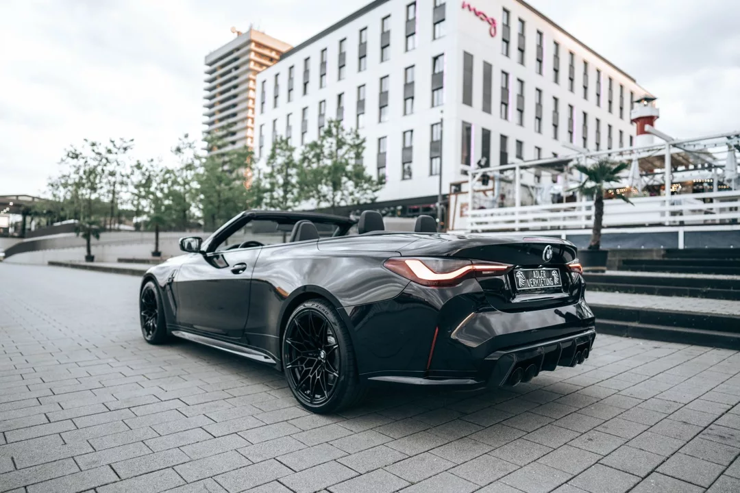 BMW M4 Competition Cabrio in Schwarz, Heckansicht mit offenem Verdeck mieten.
