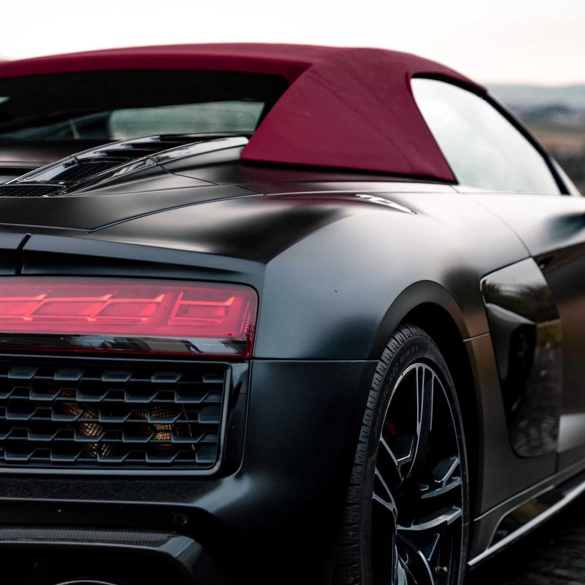 Audi R8 Spyder in Mattschwarz mit rotem Verdeck von hinten mieten