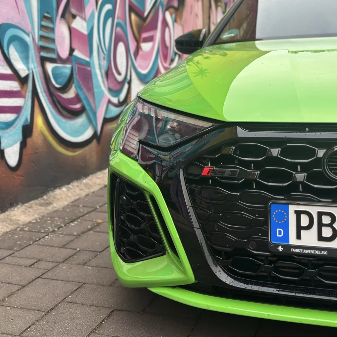 Audi RS3 Sportback in Grün mit Graffiti-Hintergrund mieten.