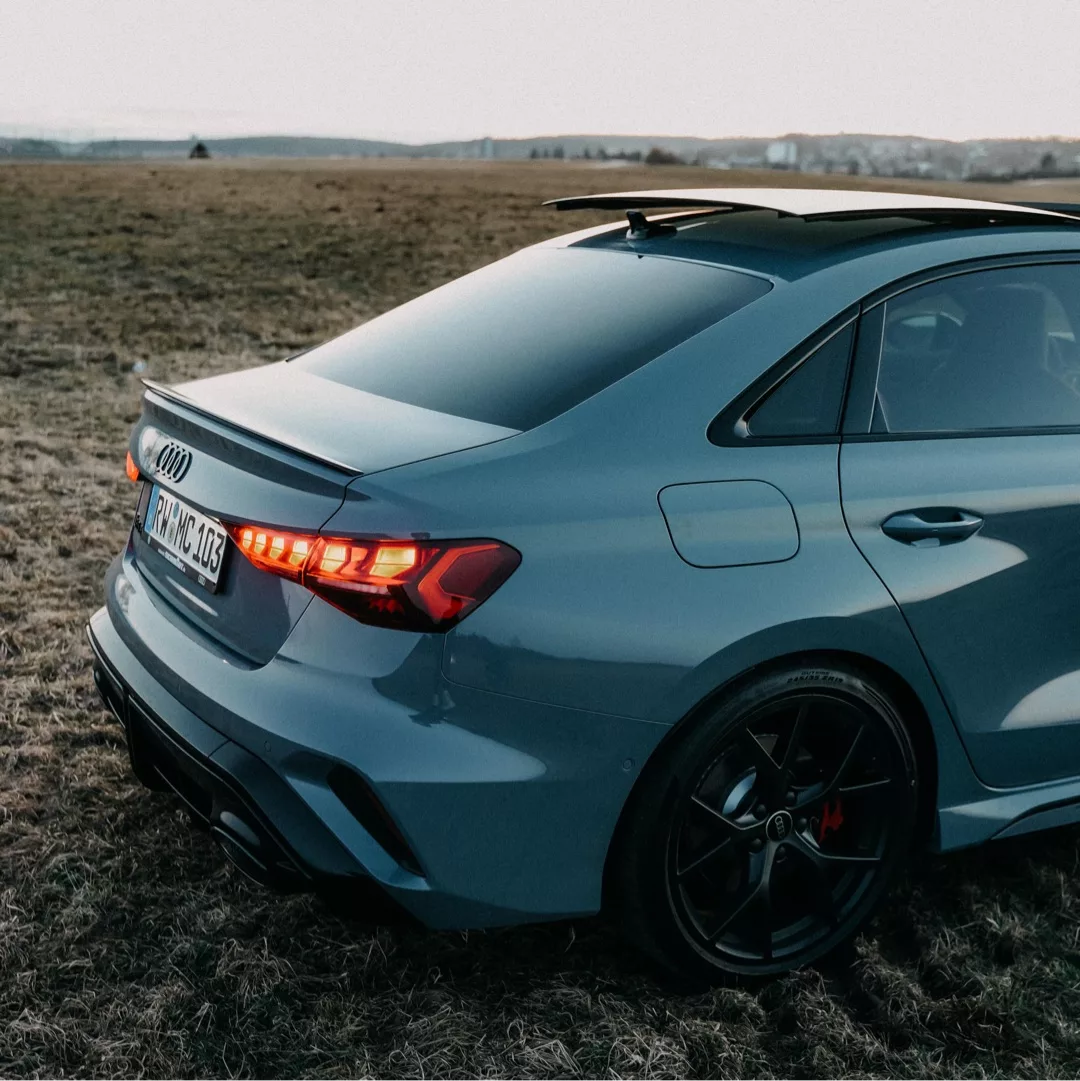 Audi RS3 Facelift in Grau, Heckansicht auf Feld mieten.