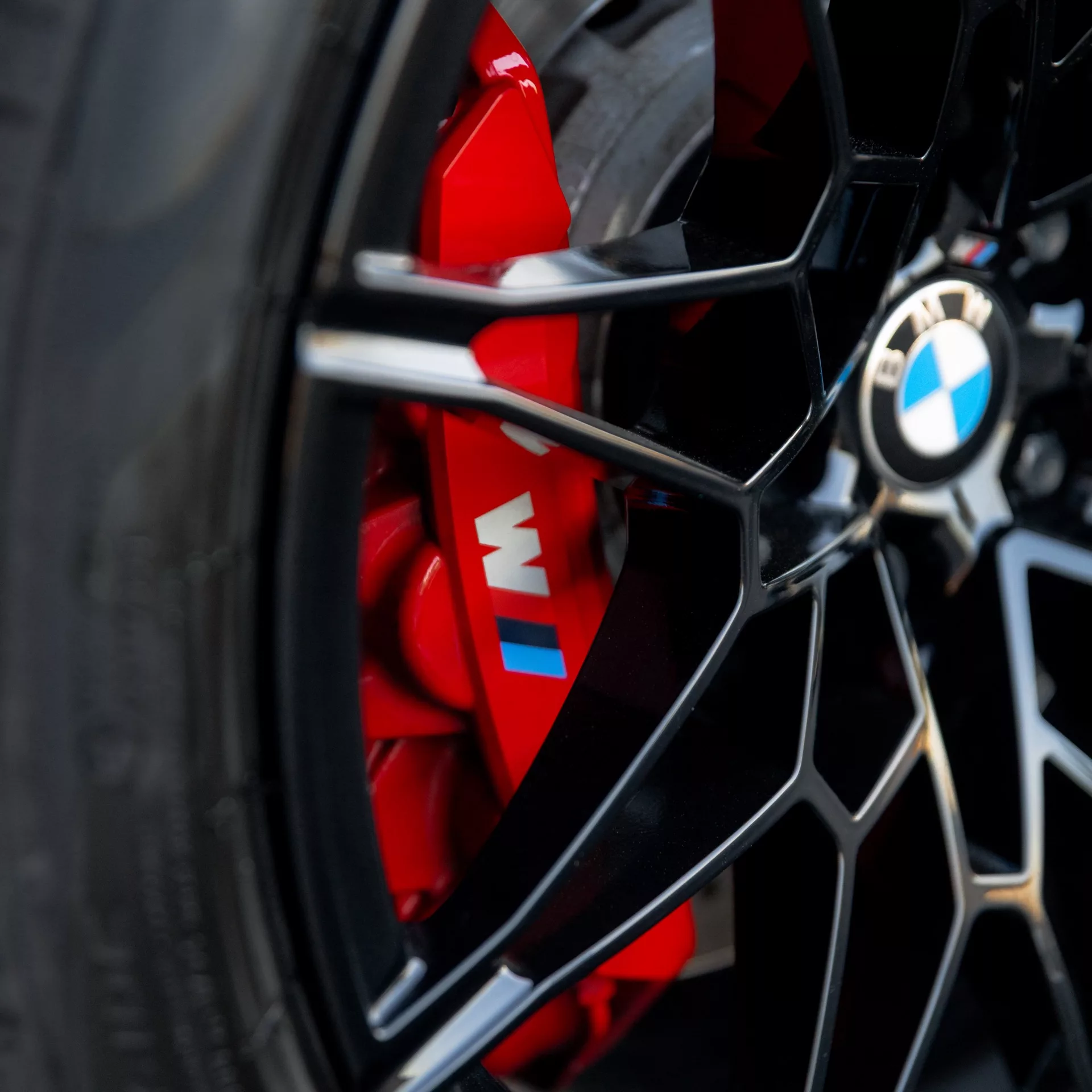 BMW M3 Competition XDrive Detail der Felge mit rotem Bremssattel mieten.