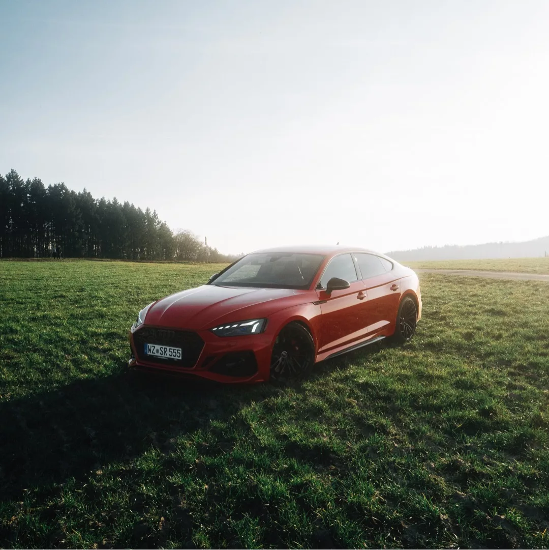 Audi RS5 Sportback in Rot auf Wiese mieten.