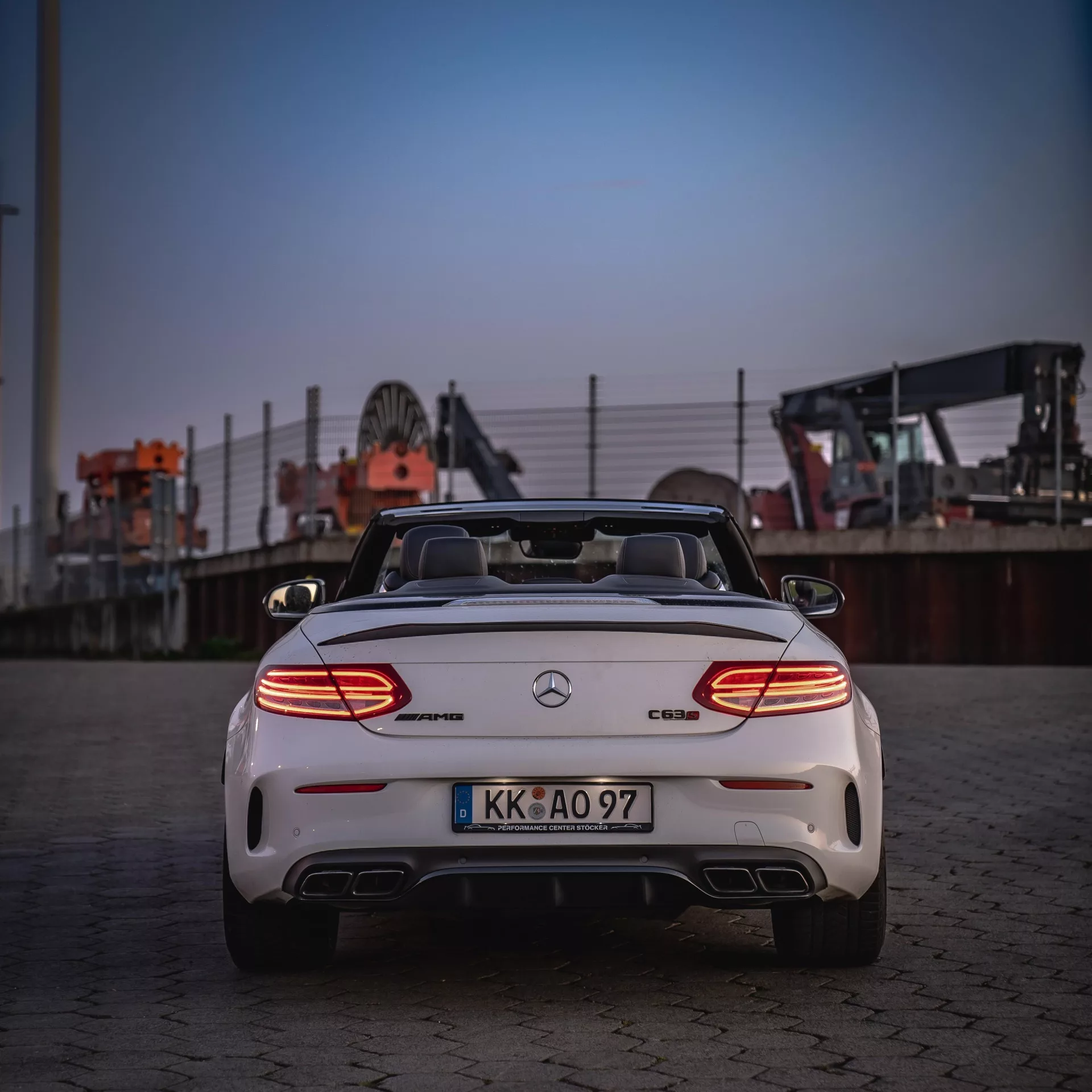 Mercedes C63s Cabrio in Weiß von hinten bei Abenddämmerung mieten