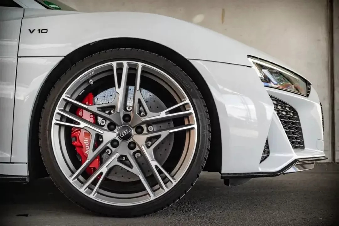 Weißer Audi R8 V10 Performance Coupé, Nahaufnahme des Vorderrads und der Bremsen.
