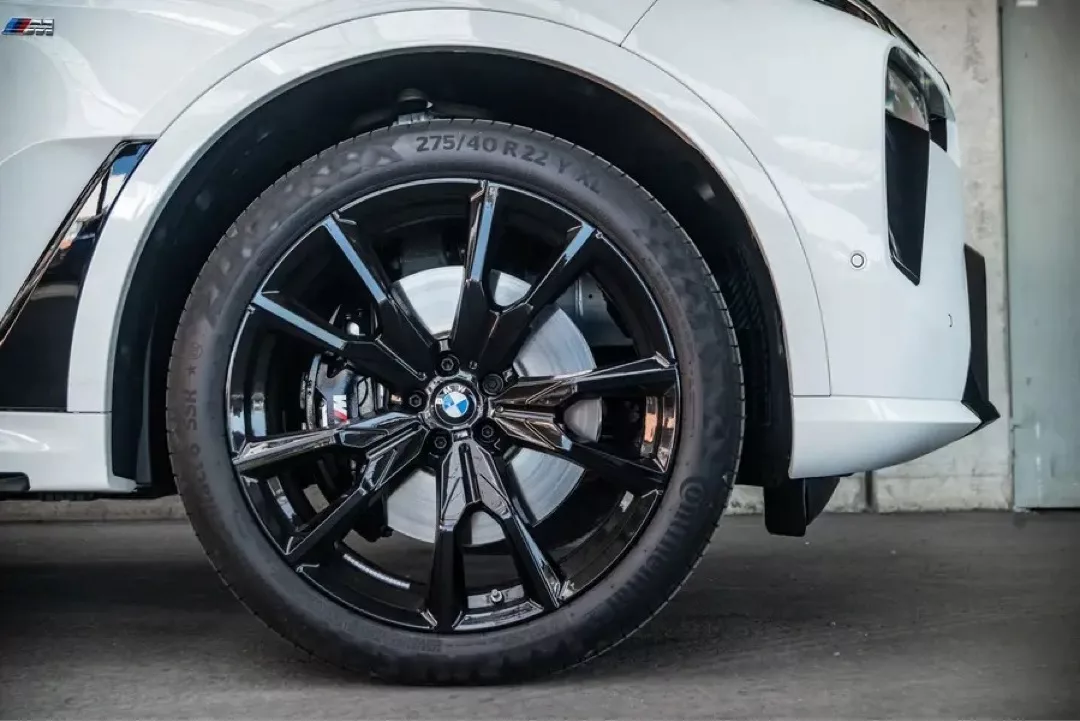 Weißer BMW X7 mit markanten schwarzen Alufelgen im Detail.