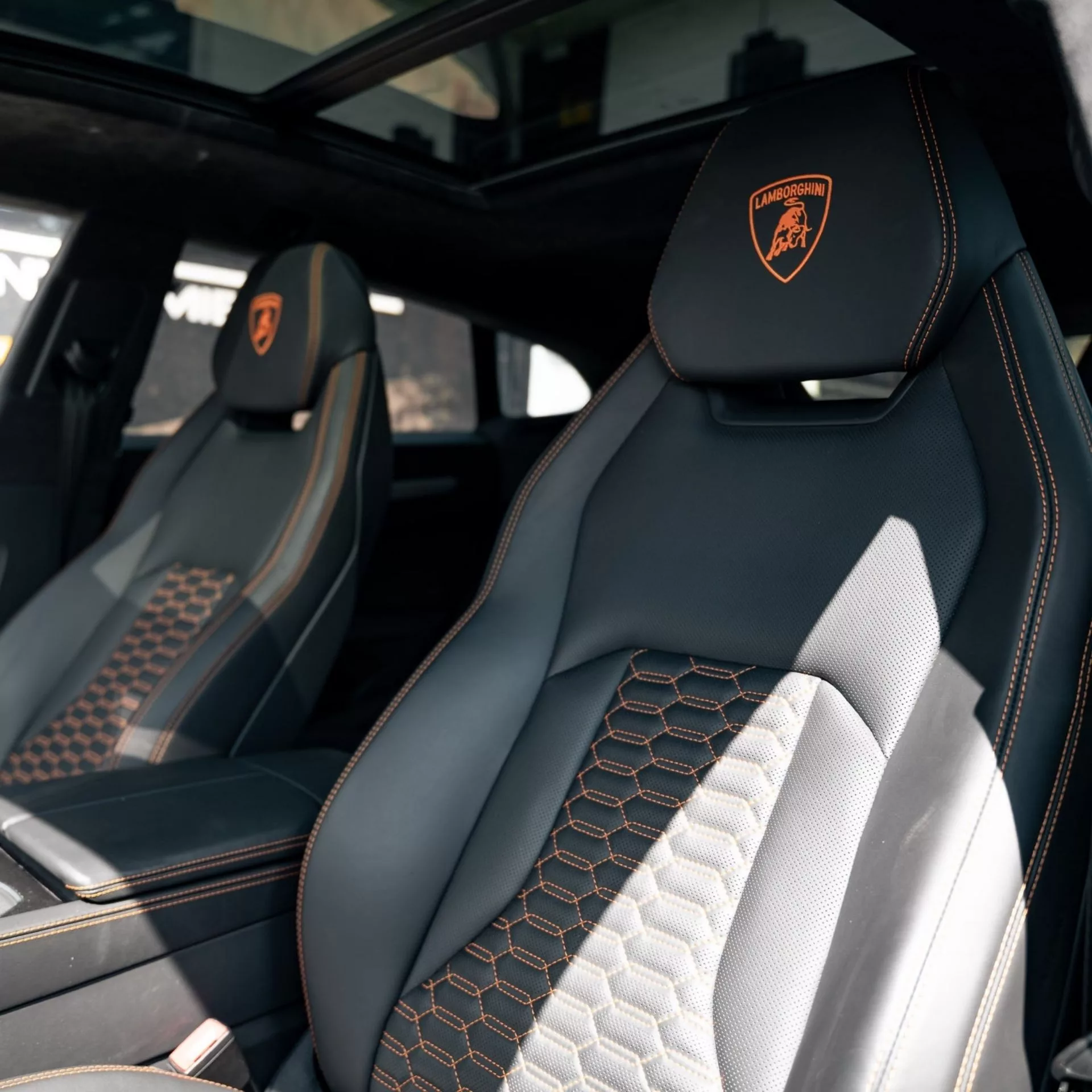 Luxuriöser Innenraum eines Lamborghini Urus mit stilvollen Sitzen und Panoramadach.