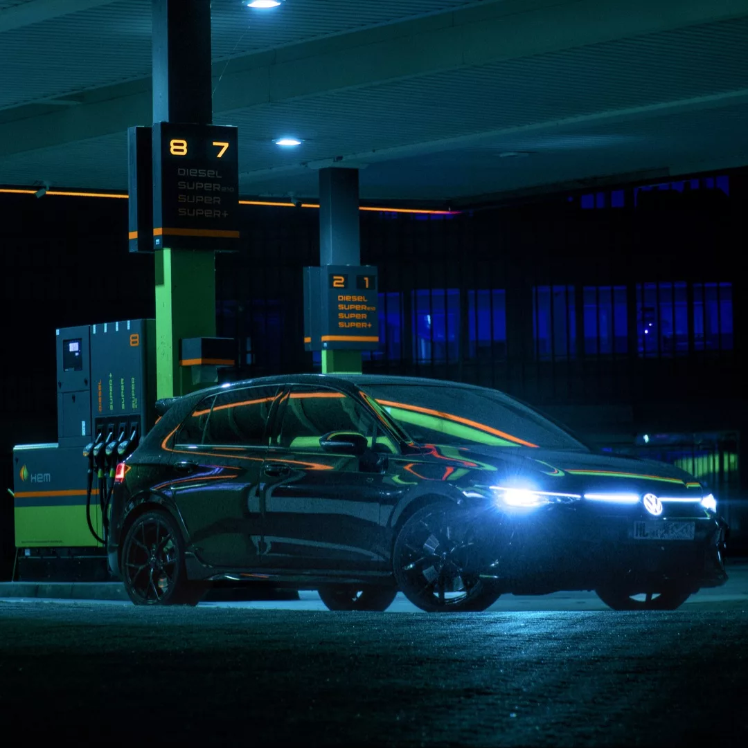 Schwarzer Golf 8 R an einer beleuchteten Tankstelle bei Nacht.