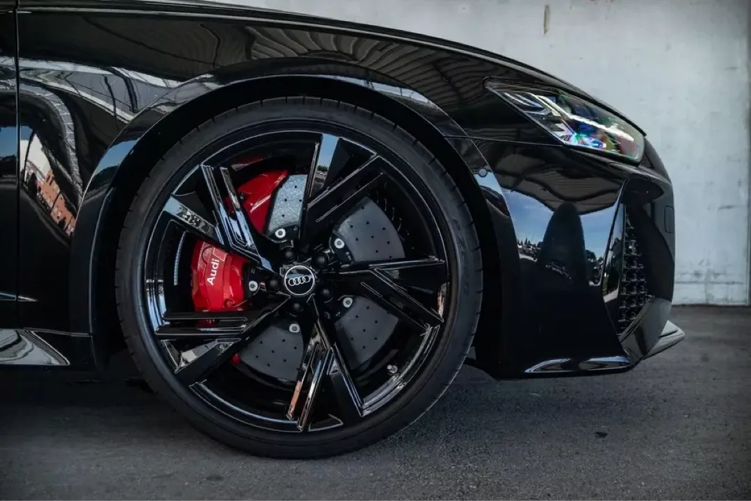 Nahaufnahme eines schwarzen Audi RS6 mit markanten Felgen und roten Bremssätteln.