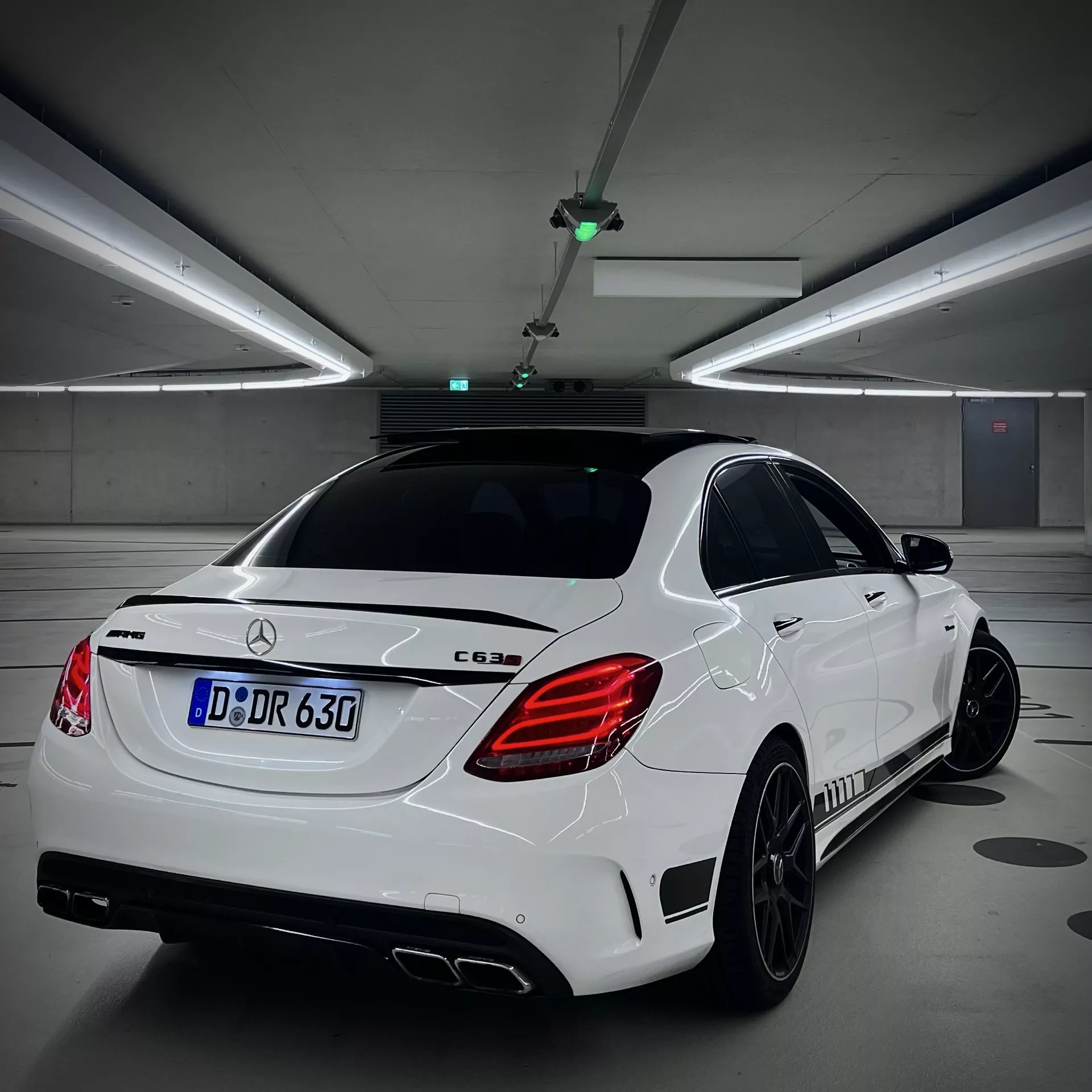 Mercedes C63 AMG in Weiß von hinten im Parkhaus mieten.
