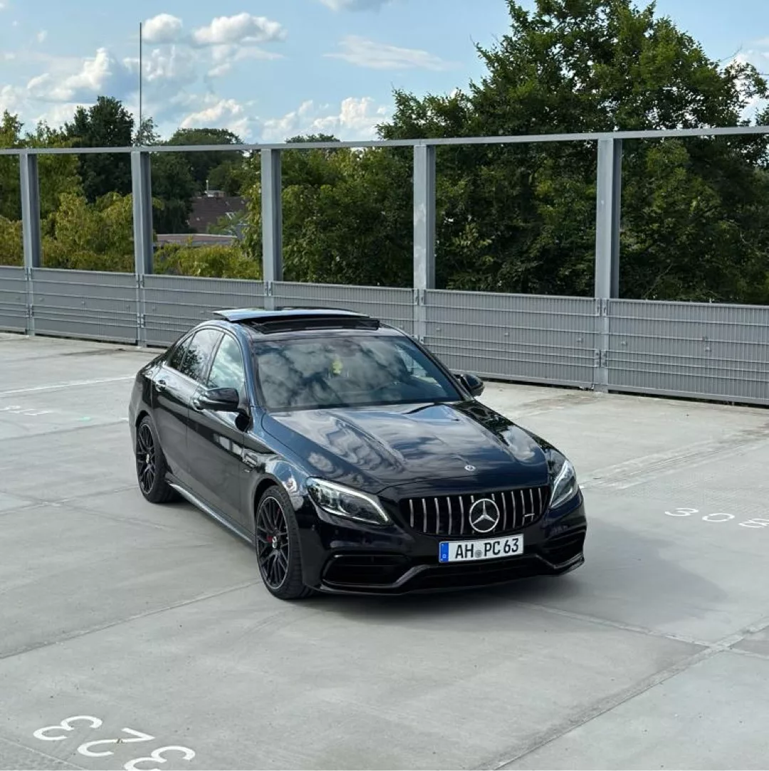 Mercedes Benz C63s AMG in Schwarz auf Parkplatz mieten.