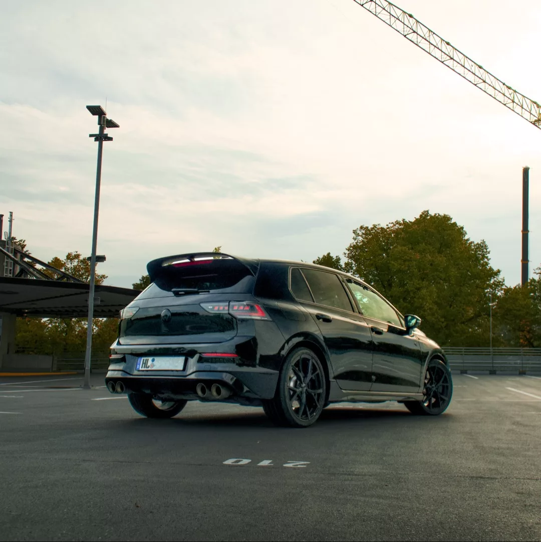 Schwarzer Golf 8 R auf einem Parkplatz bei Sonnenuntergang.