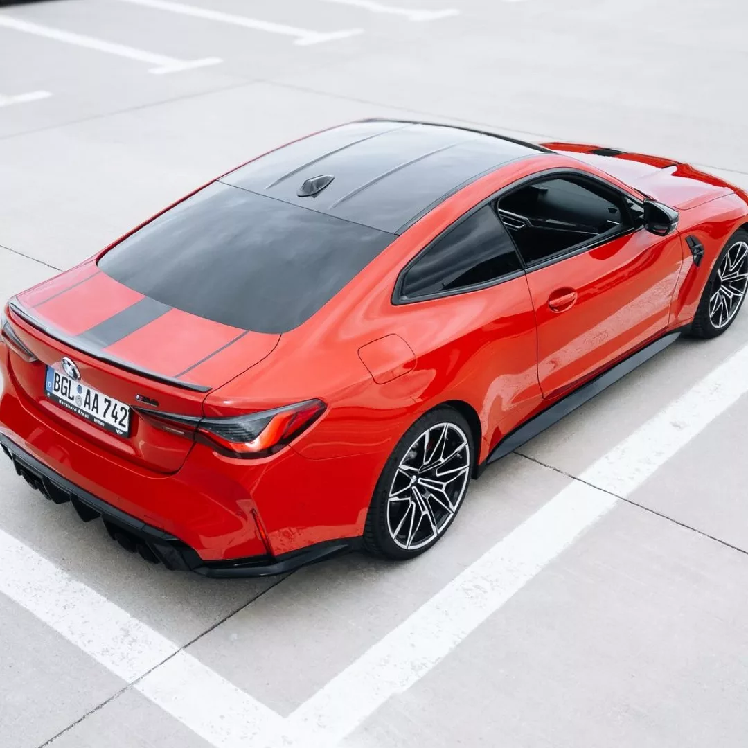 Roter BMW M4 Competition xDrive auf einem Parkplatz von oben.