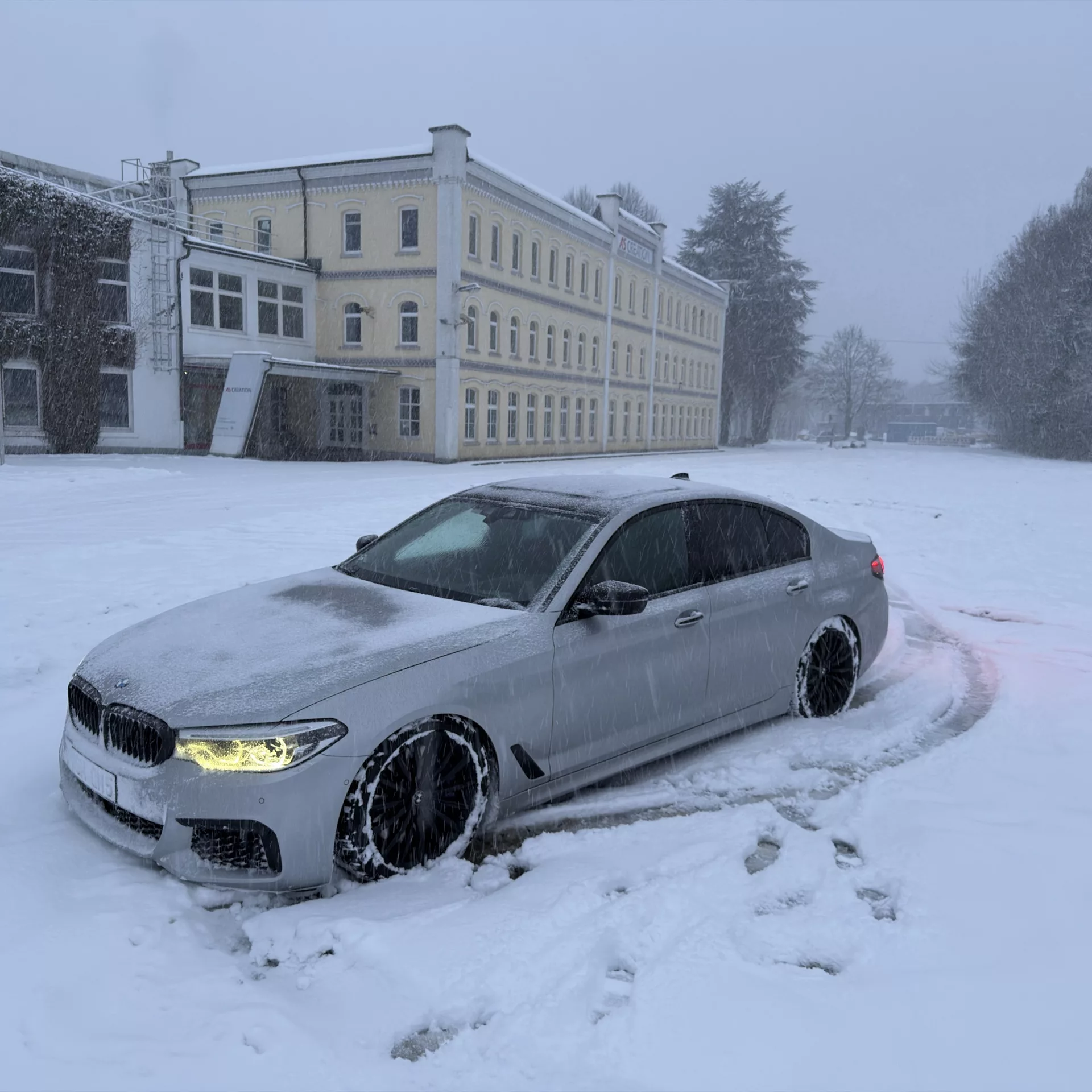 BMW m550i im Schnee, Seitenansicht, in Silber mieten.